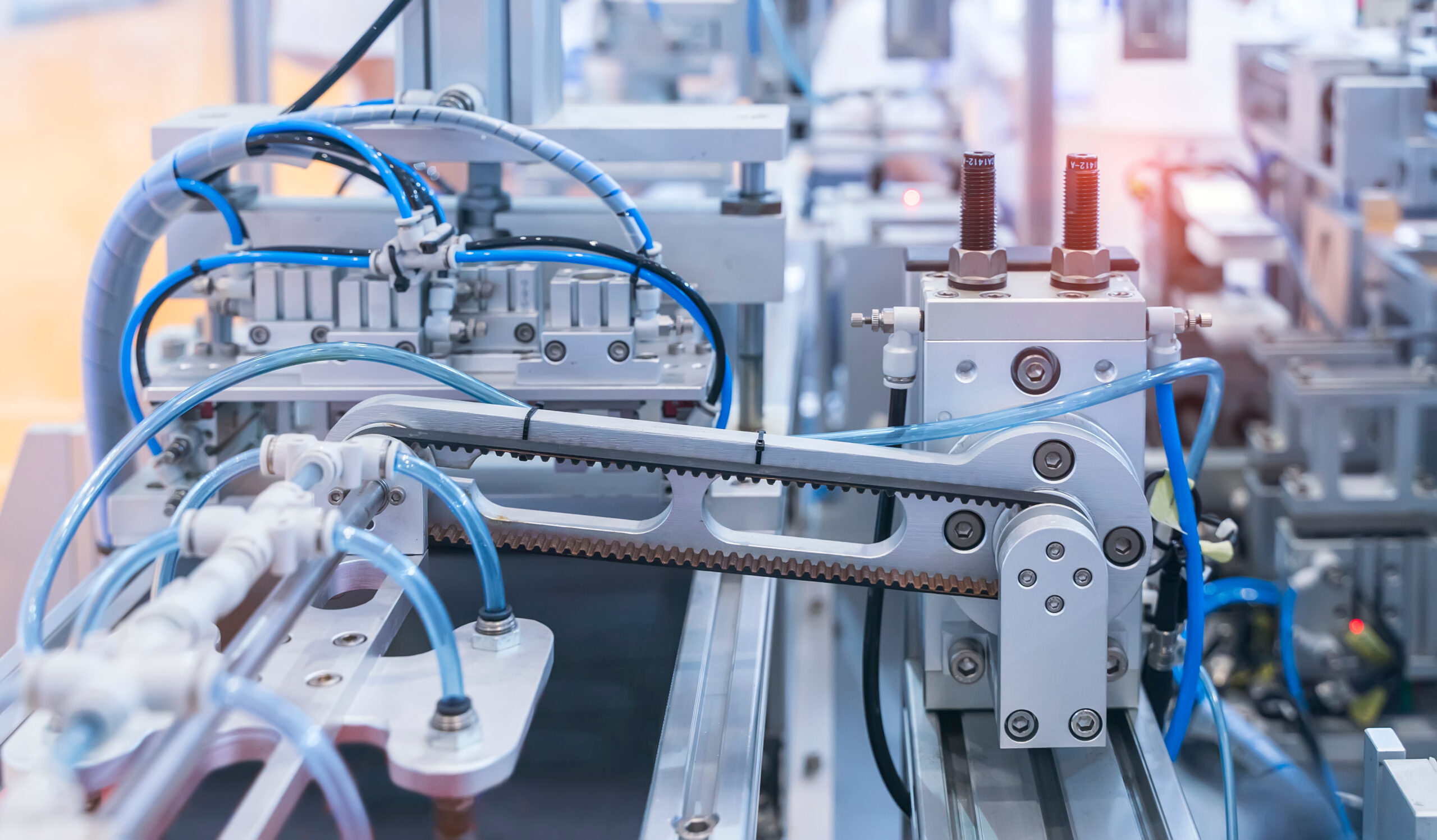 Detailansicht einer automatisierten Industrieanlage mit Pneumatikleitungen, Sensoren und mechanischen Komponenten in einer modernen Produktionsumgebung.